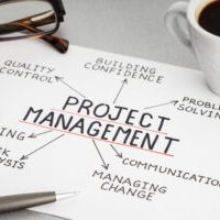Project management concept. Paper sheet with ideas or plan, cup of coffee and eyeglasses on desk